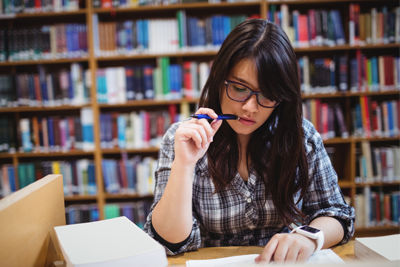 A photo of a young woman studying her notes in a library