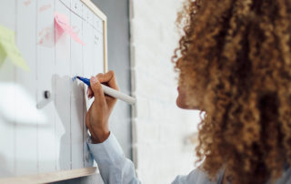 A photo of a young woman writing on a whiteboard