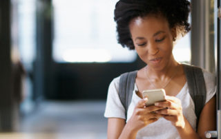 A photo of a young woman looking at her cellphone.