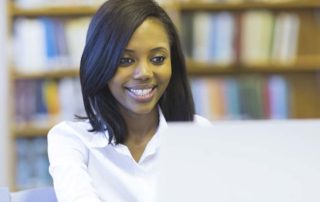 An image of a student working on her laptop in a library.